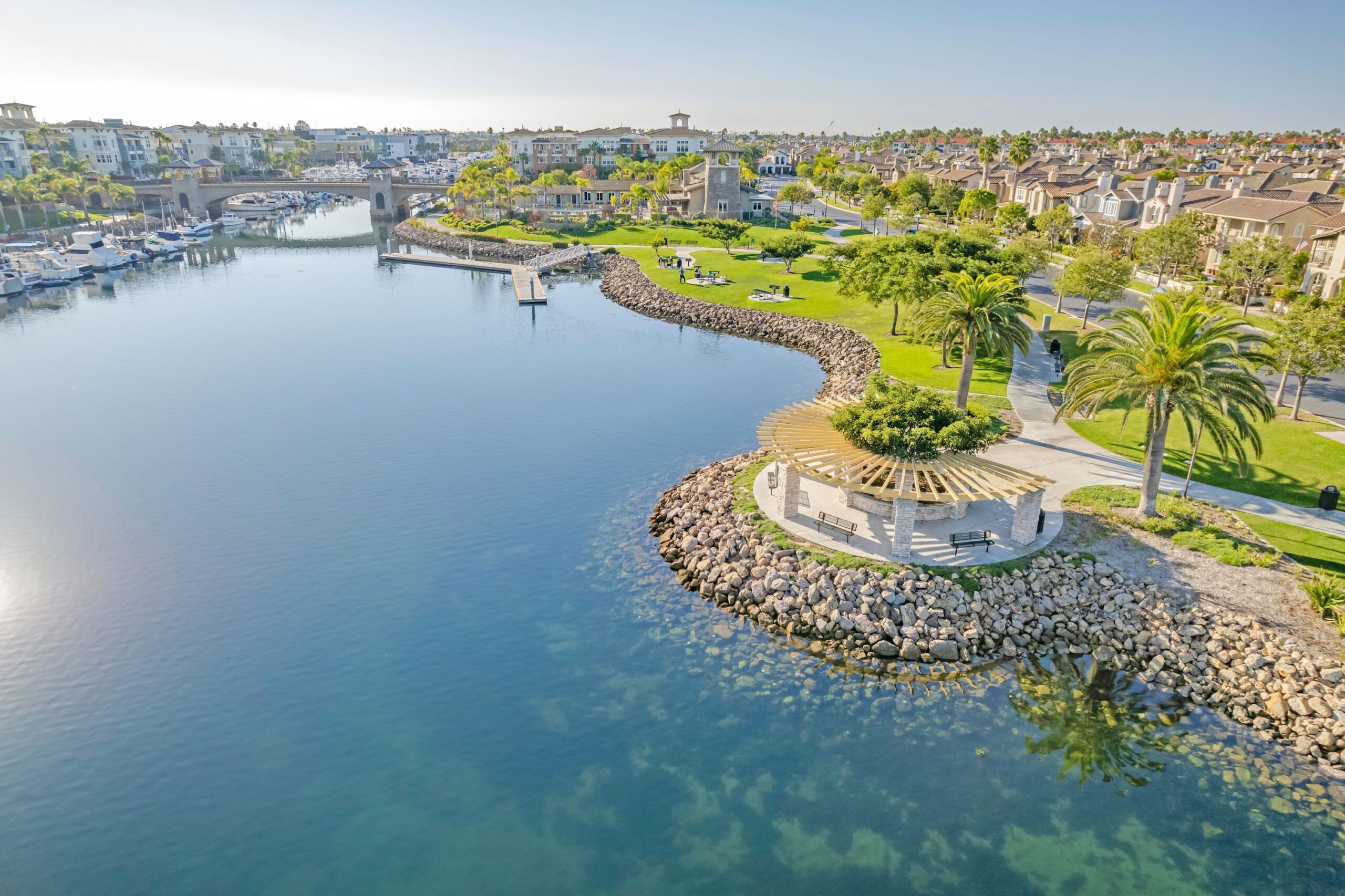 A park at Oxnard harbor with boats docked on one side and a neighborhood on the other.