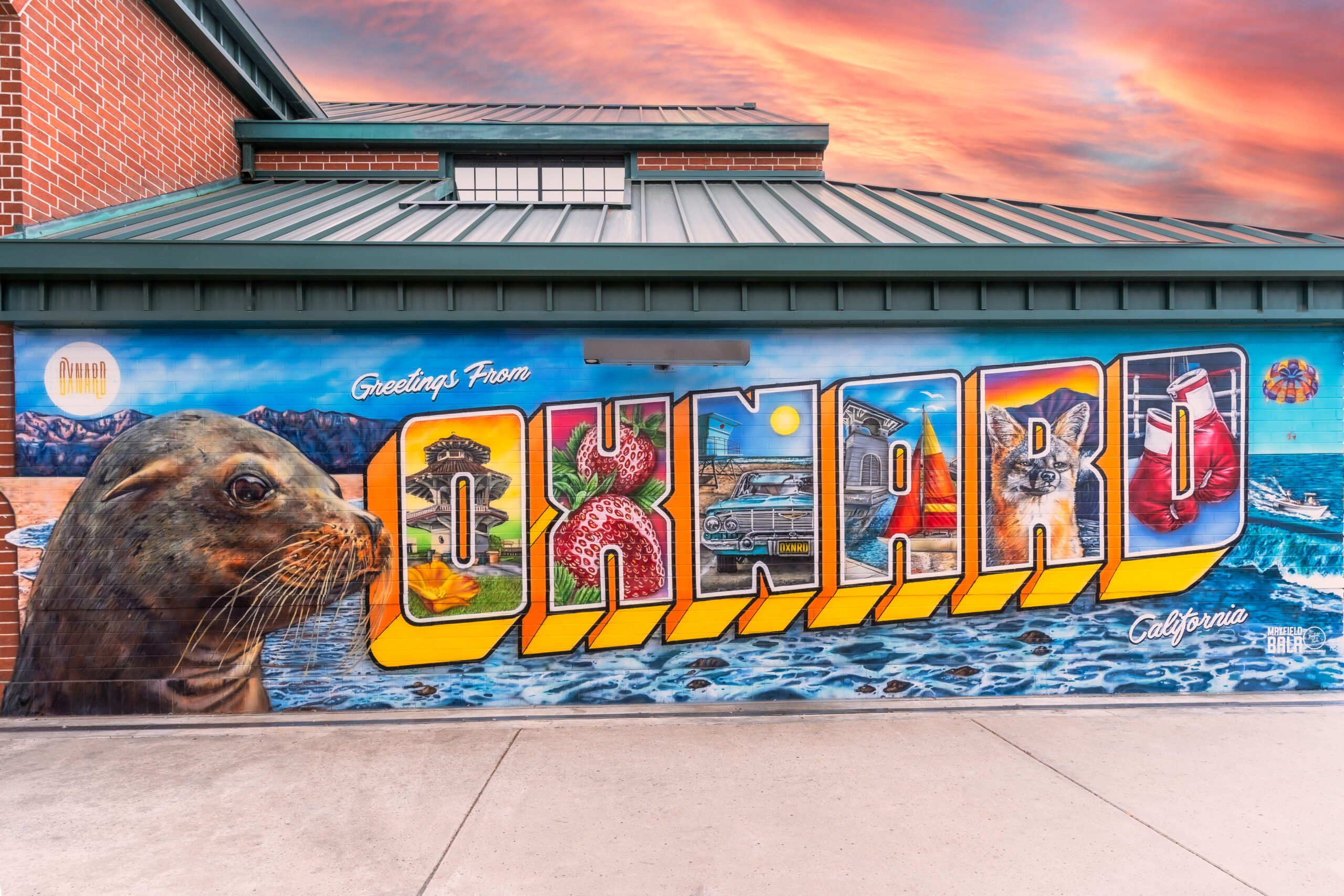A wall with a graphic on it depicting different aspects of the city and words that say "Greetings from Oxnard California".