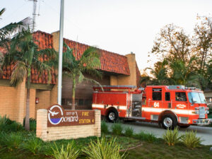 Fire station 4 with palm trees in the front, engine 64 parked in the driveway and the City of Oxnard sign located on the lawn.