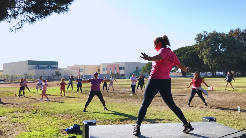 A group exercising in an open field in front of Lemonwood School.