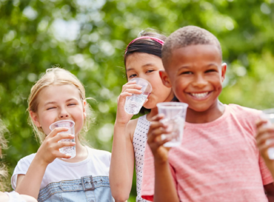 A group of kids drinking water out of clear cups.
