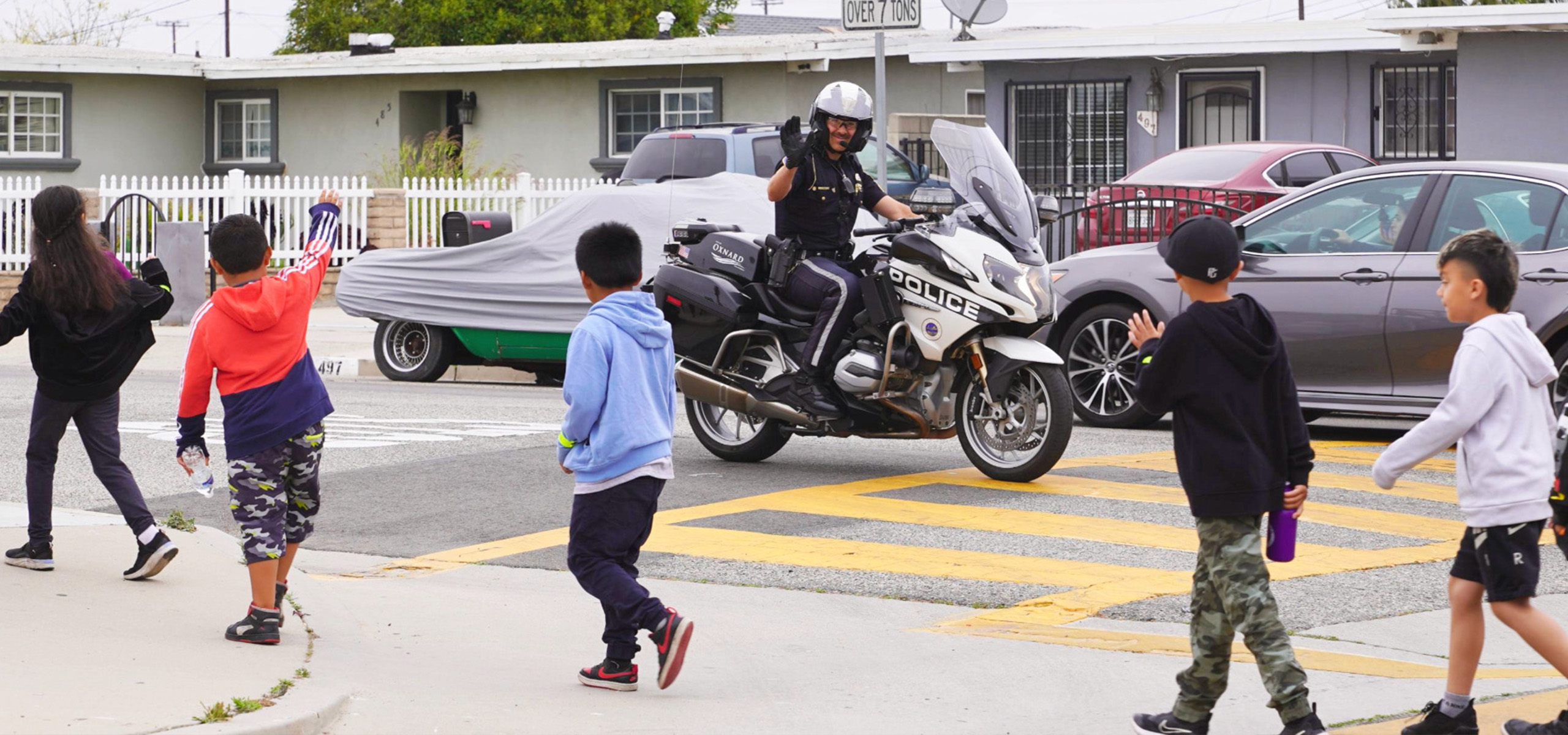 Police Officer on a motorcycle waving to children
